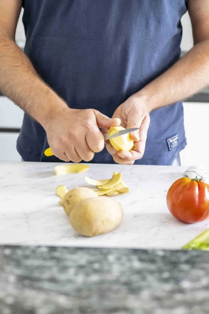 A man slicing potatoes on a cutting board.