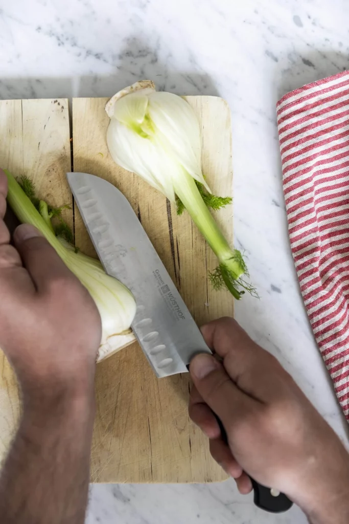 A person slicing an onion on a cutting board.