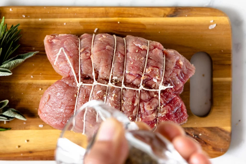A person is slicing a piece of meat on a cutting board.