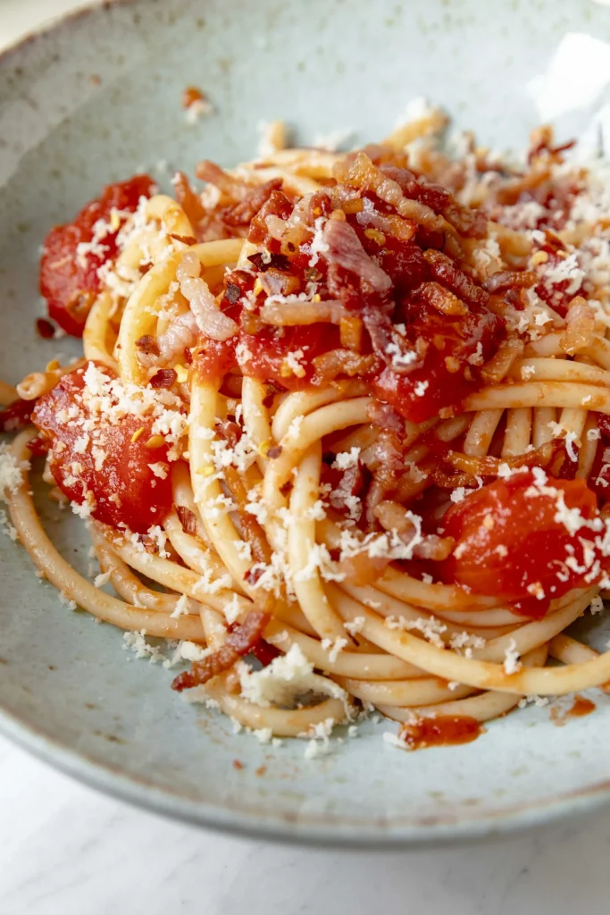 A bowl of spaghetti with tomatoes and parmesan cheese.