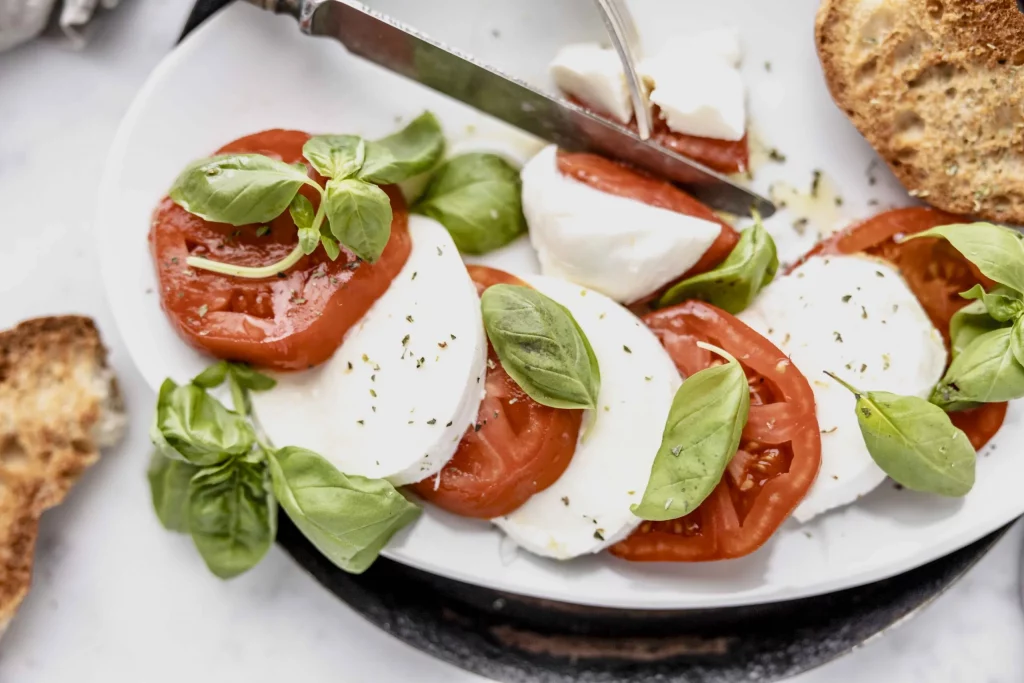 Tomatoes, mozzarella and basil on a white plate.