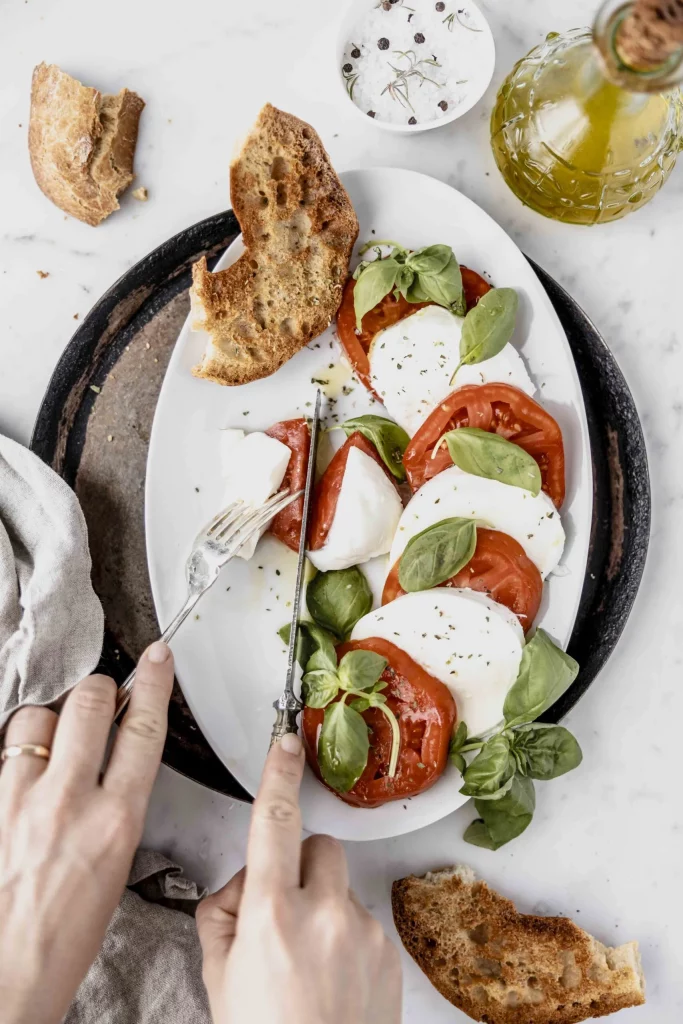 A plate with tomato, mozzarella and basil on it.