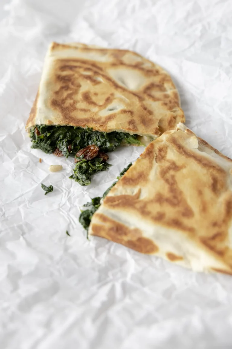 A quesadilla with spinach on top of a piece of paper.