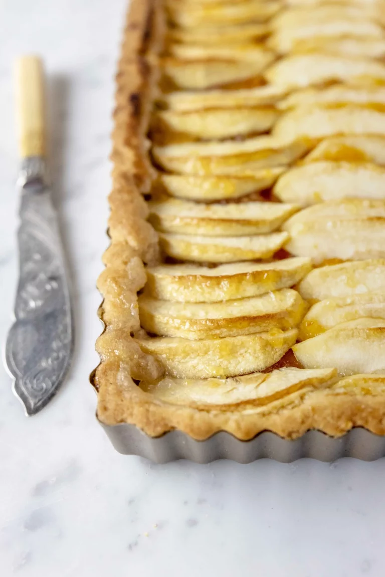 A tart with apples and a knife on top.