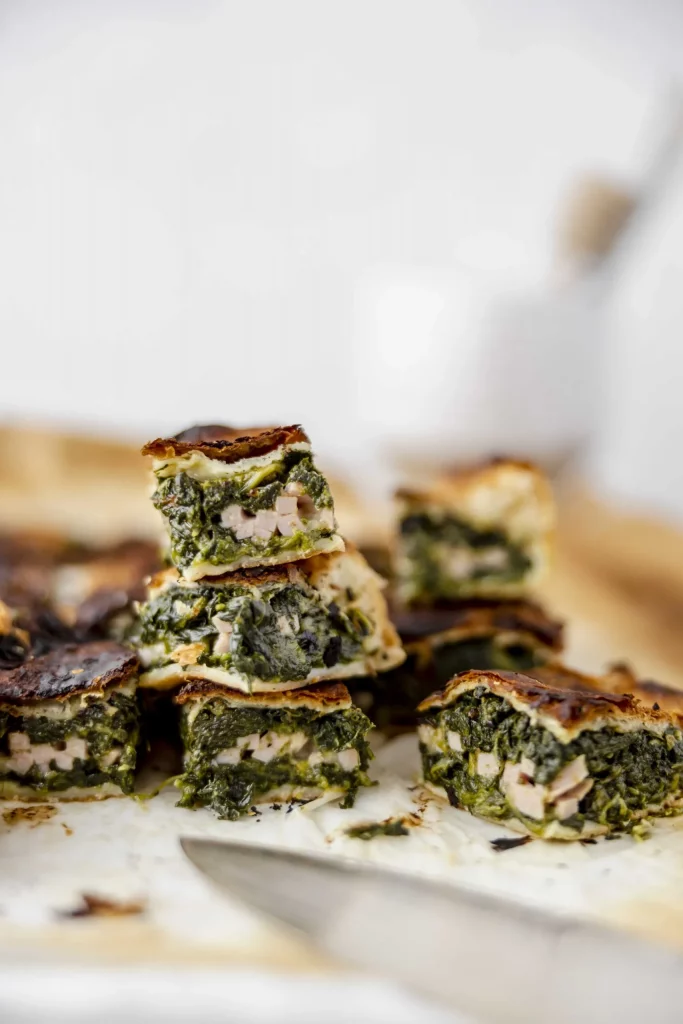 A stack of spinach and chicken tarts on a plate.
