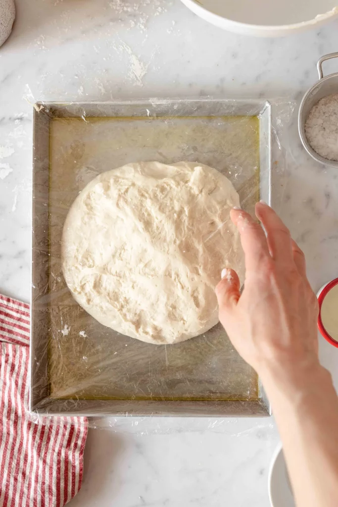 A person kneading dough on a baking sheet.