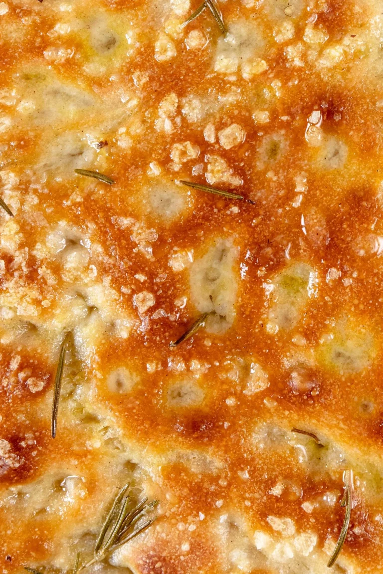 A close up of a pizza with rosemary on it.