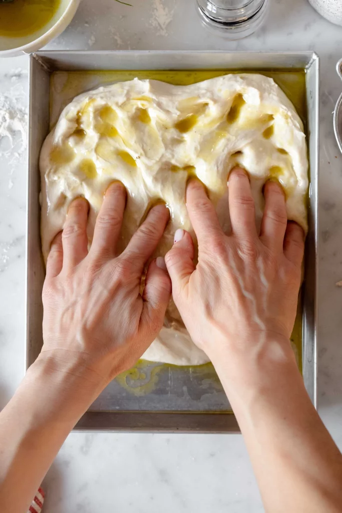 A person's hands are putting dough on a baking sheet.