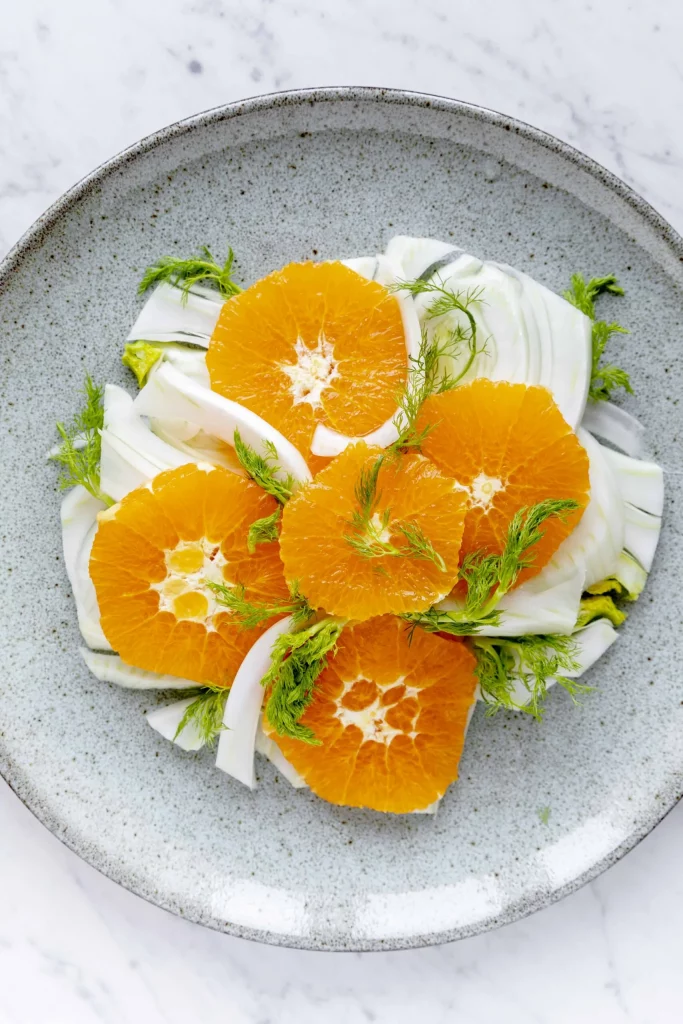 A plate with oranges and fennel on it.