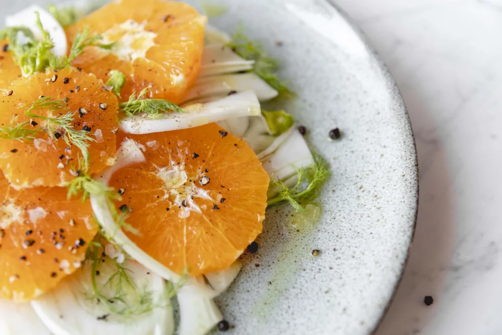 A plate with oranges and fennel on it.