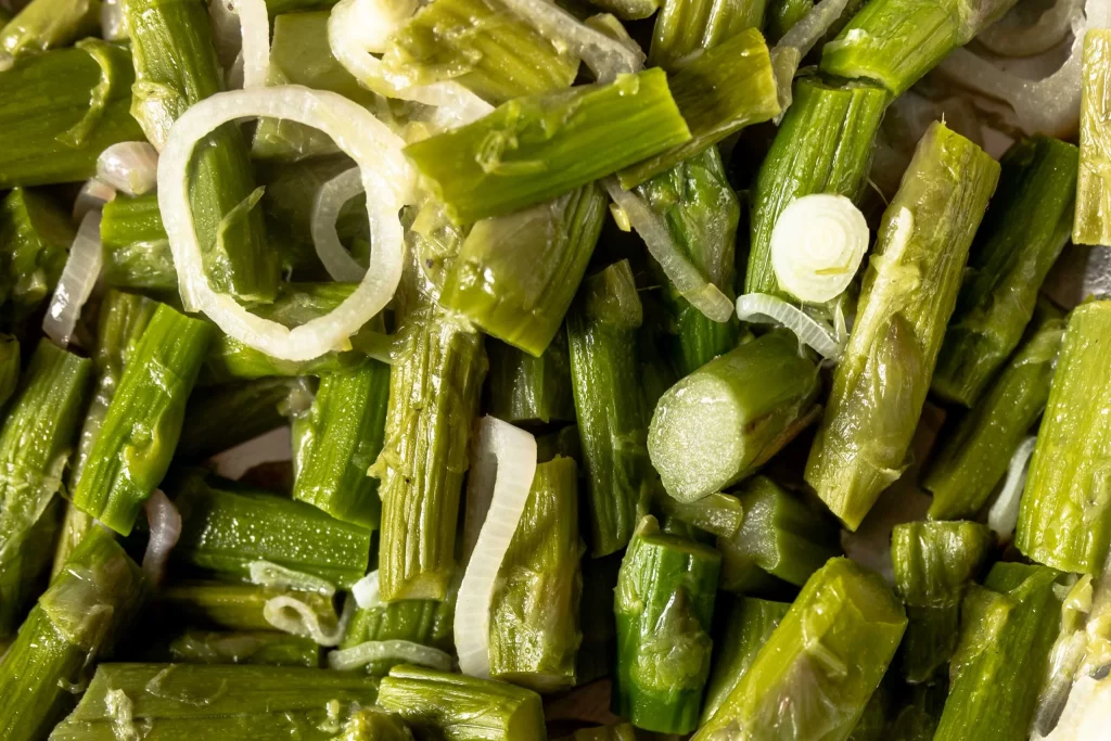 A close up of green asparagus and onions.