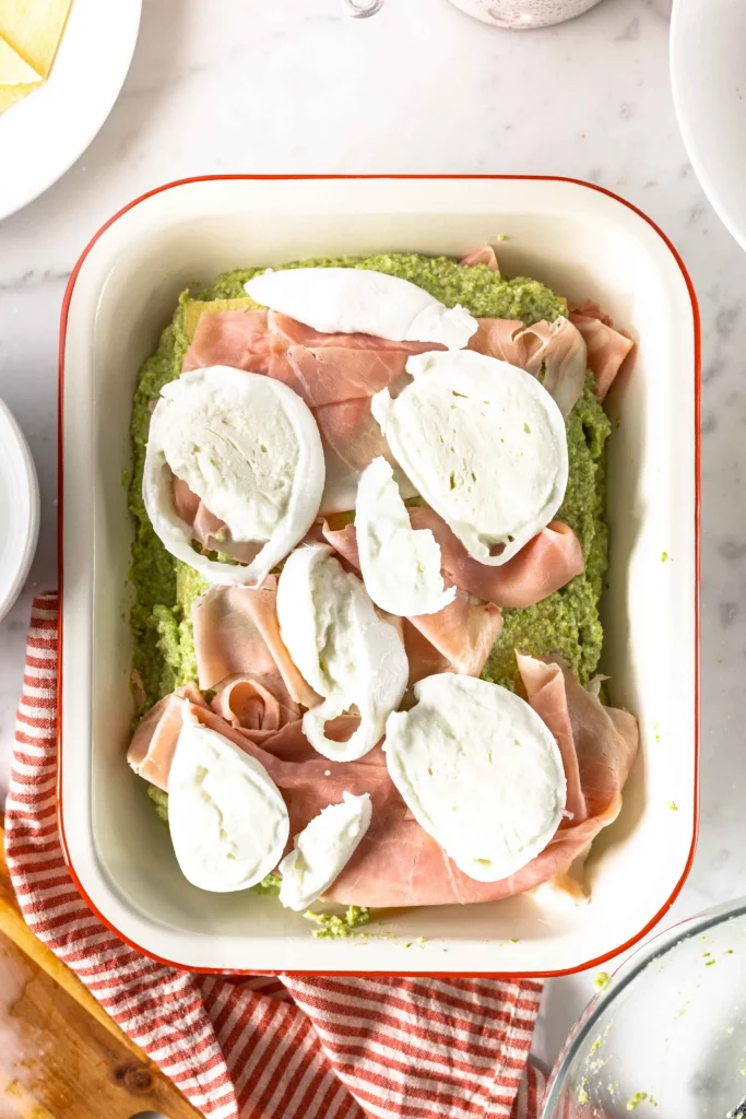 A dish with ham, eggs and greens on a table.