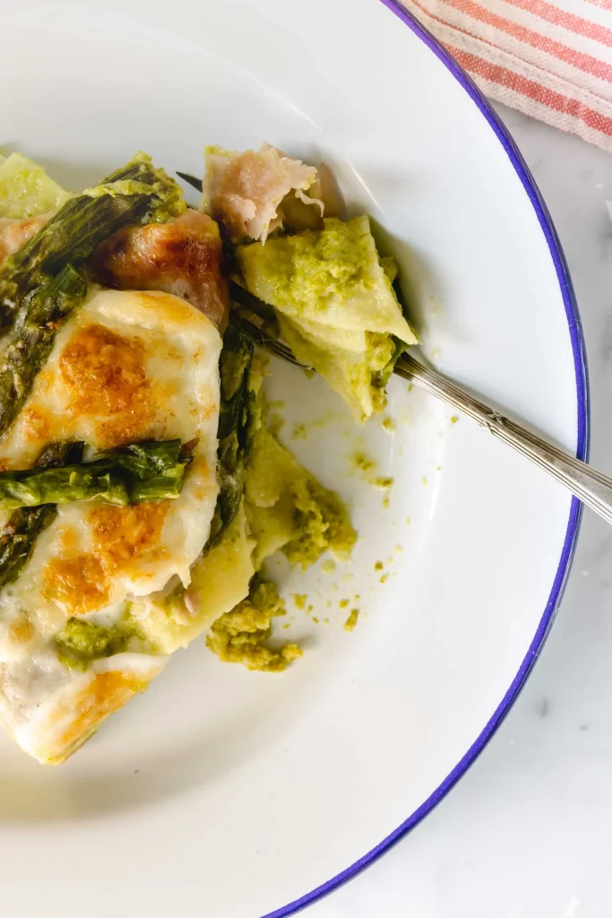 A plate of asparagus and pesto lasagna with a fork.
