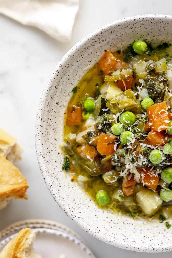 A bowl of soup with vegetables and bread.