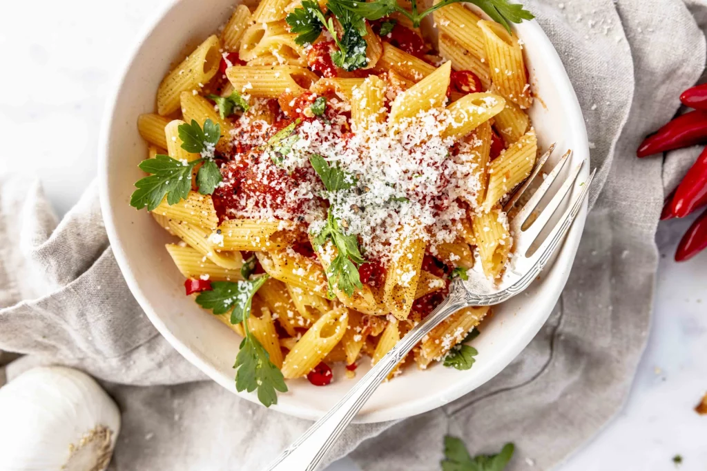 A bowl of pasta with tomatoes, garlic and parmesan.