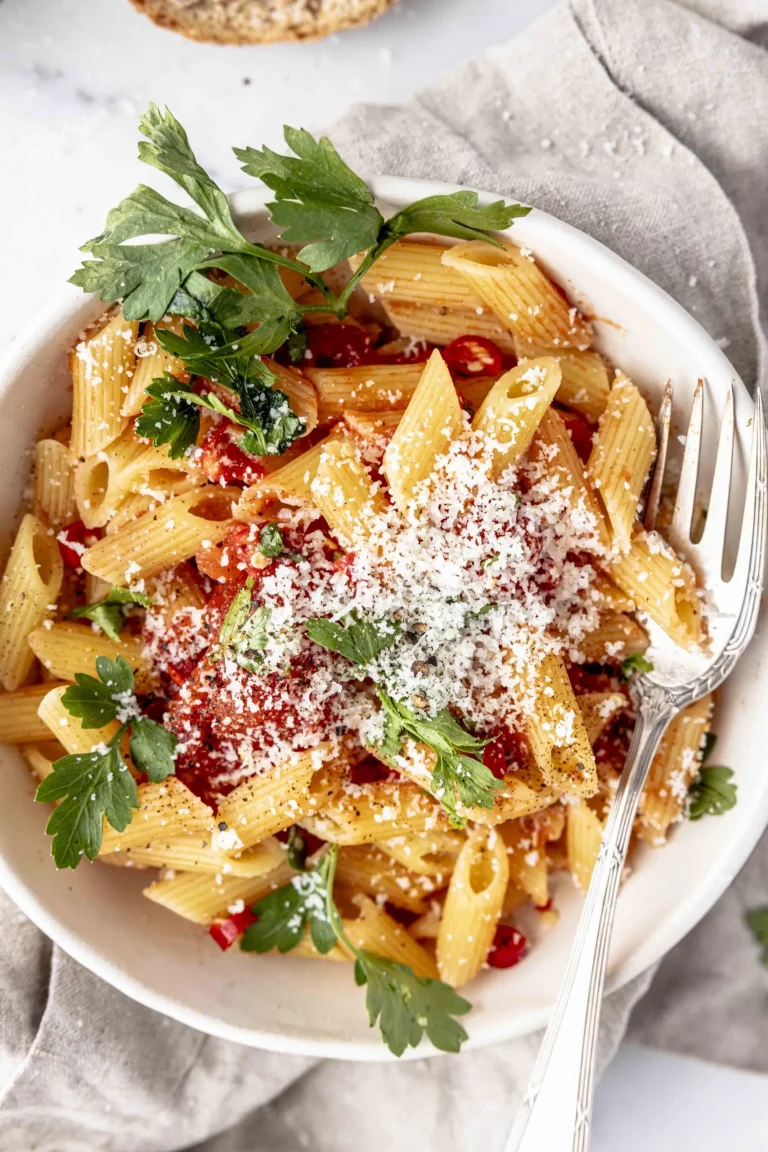 A bowl of pasta with parmesan and parsley.