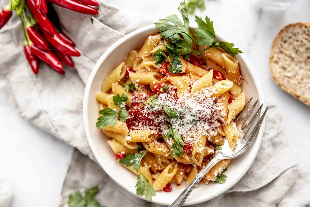A bowl of pasta with peppers and parmesan cheese.