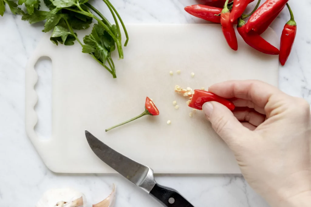 A person is slicing peppers on a cutting board.