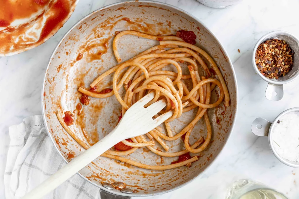 Spaghetti in a pan with sauce and a fork.