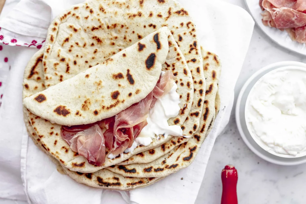 A plate of pita bread with ham and sour cream.