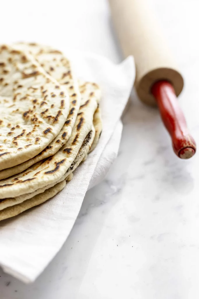 A stack of flatbreads with a rolling pin.