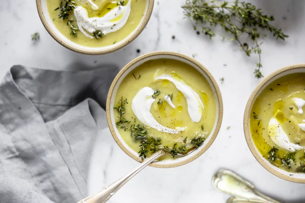 Three bowls of soup with sour cream and thyme.