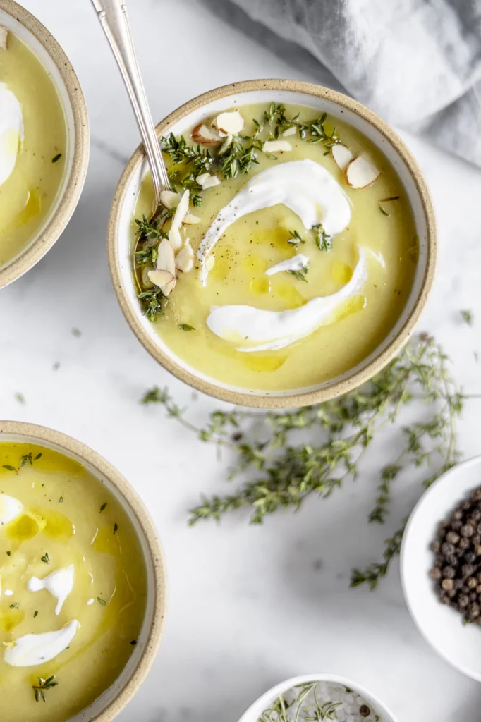 Three bowls of soup with sour cream and herbs.