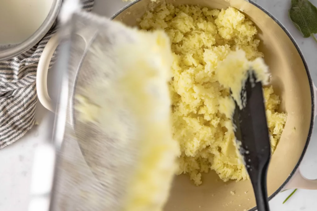 A bowl of mashed potatoes being stirred