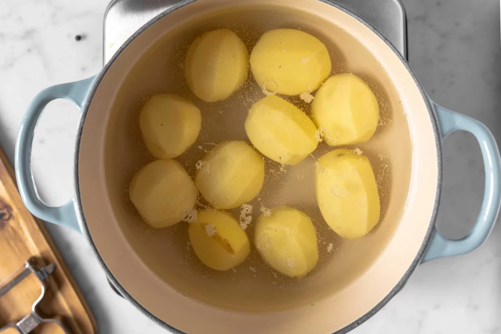 Boiled potatoes for mashed potatoes on a marble countertop.