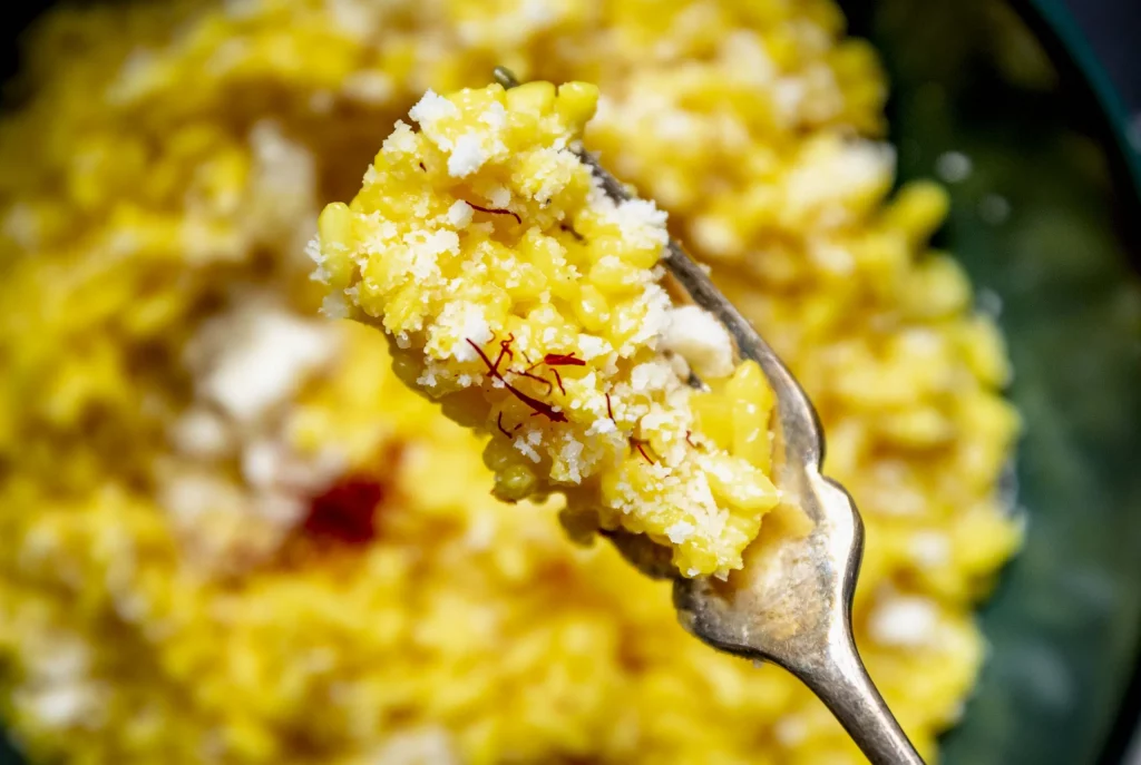 A spoon full of yellow rice in a bowl.