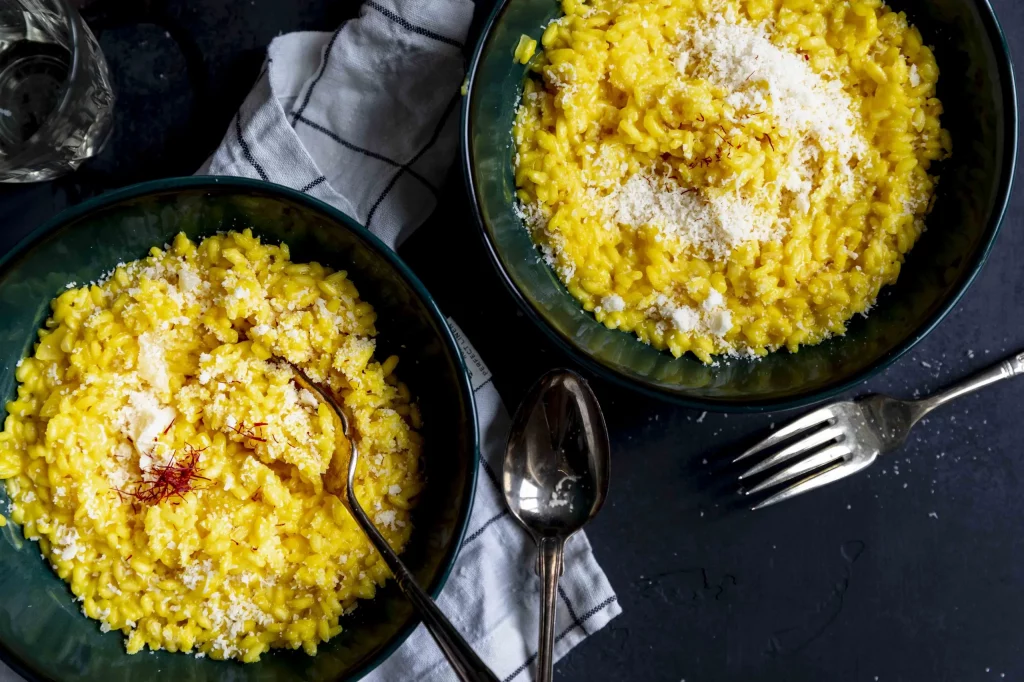 Two bowls of yellow risotto on a table.