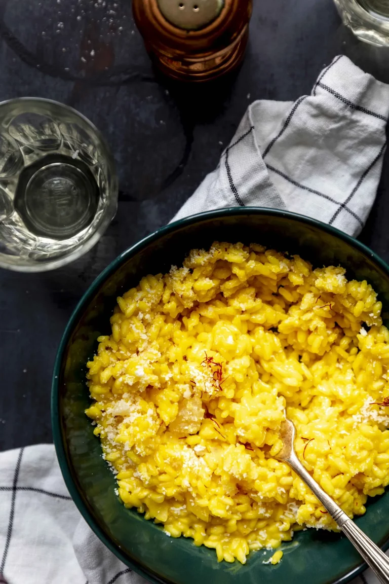 A bowl of yellow risotto with a spoon.