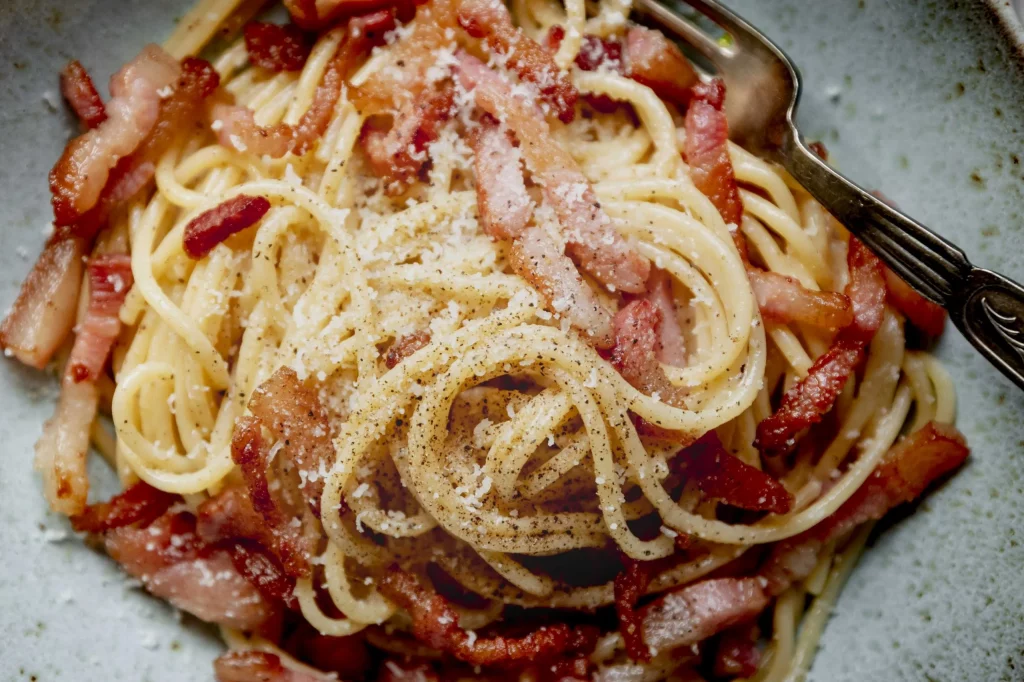 A plate of spaghetti with bacon and parmesan.