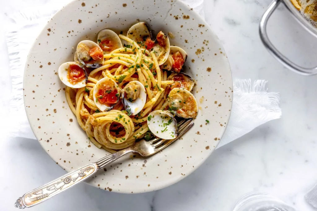 A plate of spaghetti with clams and tomatoes.
