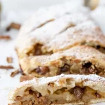 A slice of apple pie with powdered sugar and cinnamon.