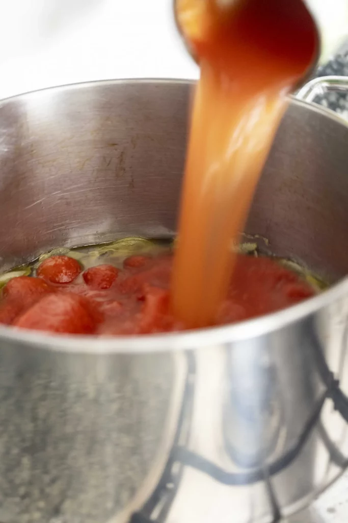 Tomato sauce being poured into a pot.