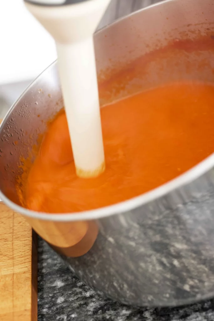 A red sauce being poured into a bowl.