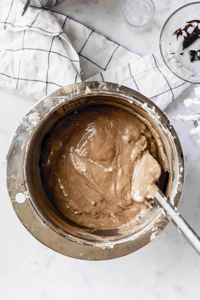 A bowl of chocolate batter with a spoon in it, ready to be transformed into a delicious tenerina cake.
