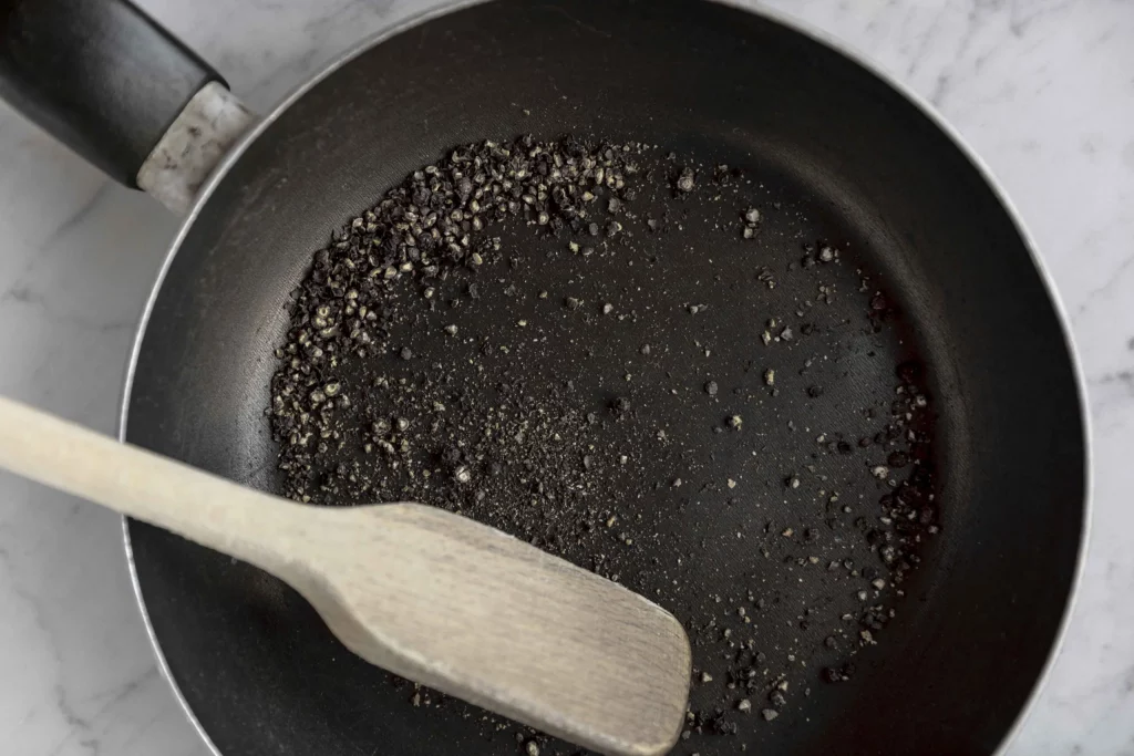 A frying pan with a wooden spoon in it.