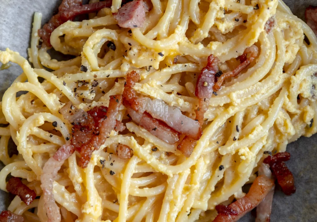 A plate of spaghetti with bacon and eggs.