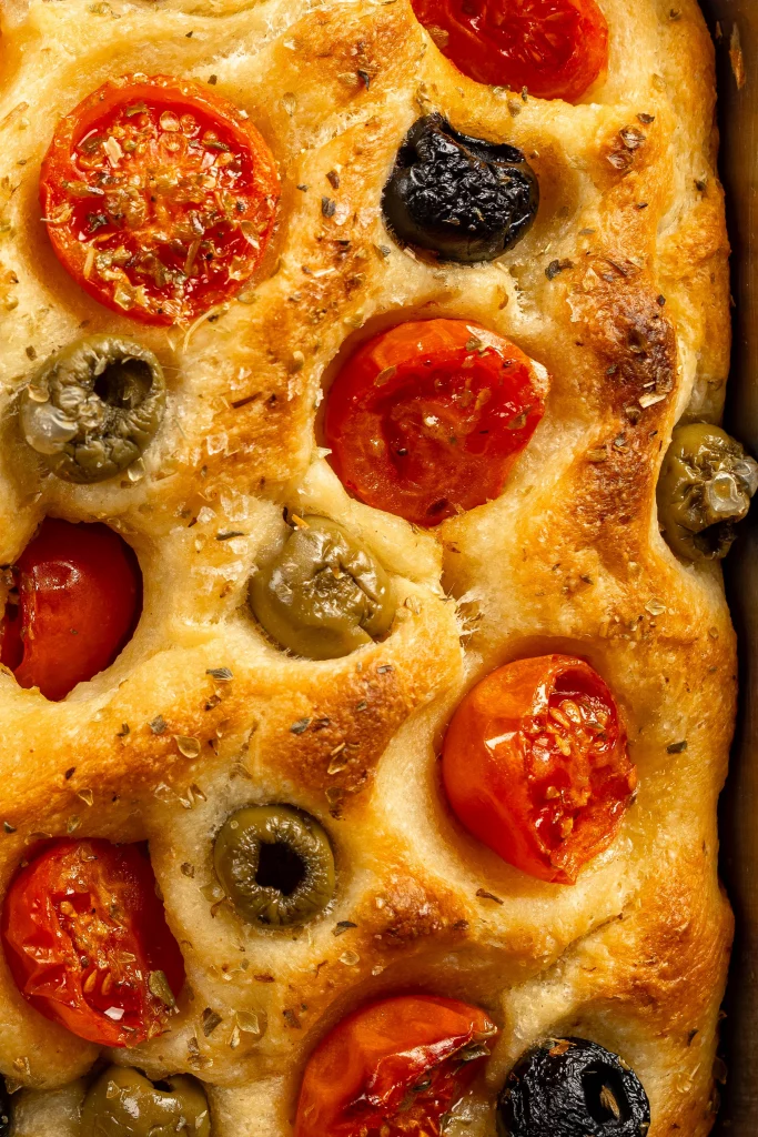 Homemade focaccia bread topped with cherry tomatoes, olives, and herbs.