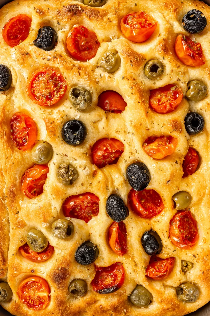 Vertical Close up of apulian flatbreadwith olives and cherry tomatoes.