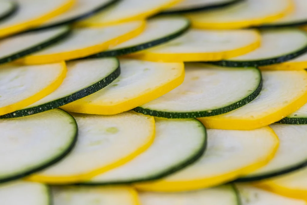 Thinly sliced zucchini arranged in an overlapping pattern, showcasing their yellow and green edges.